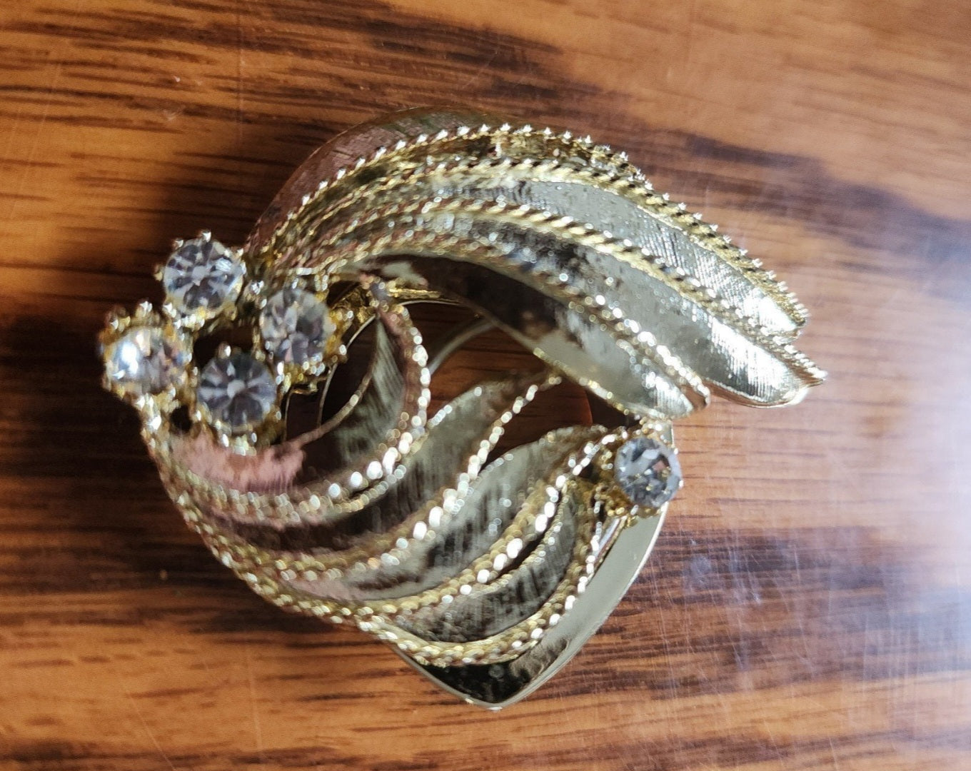 Elegant gold-tone Scarf Clip features sparkling rhinestones and a unique design