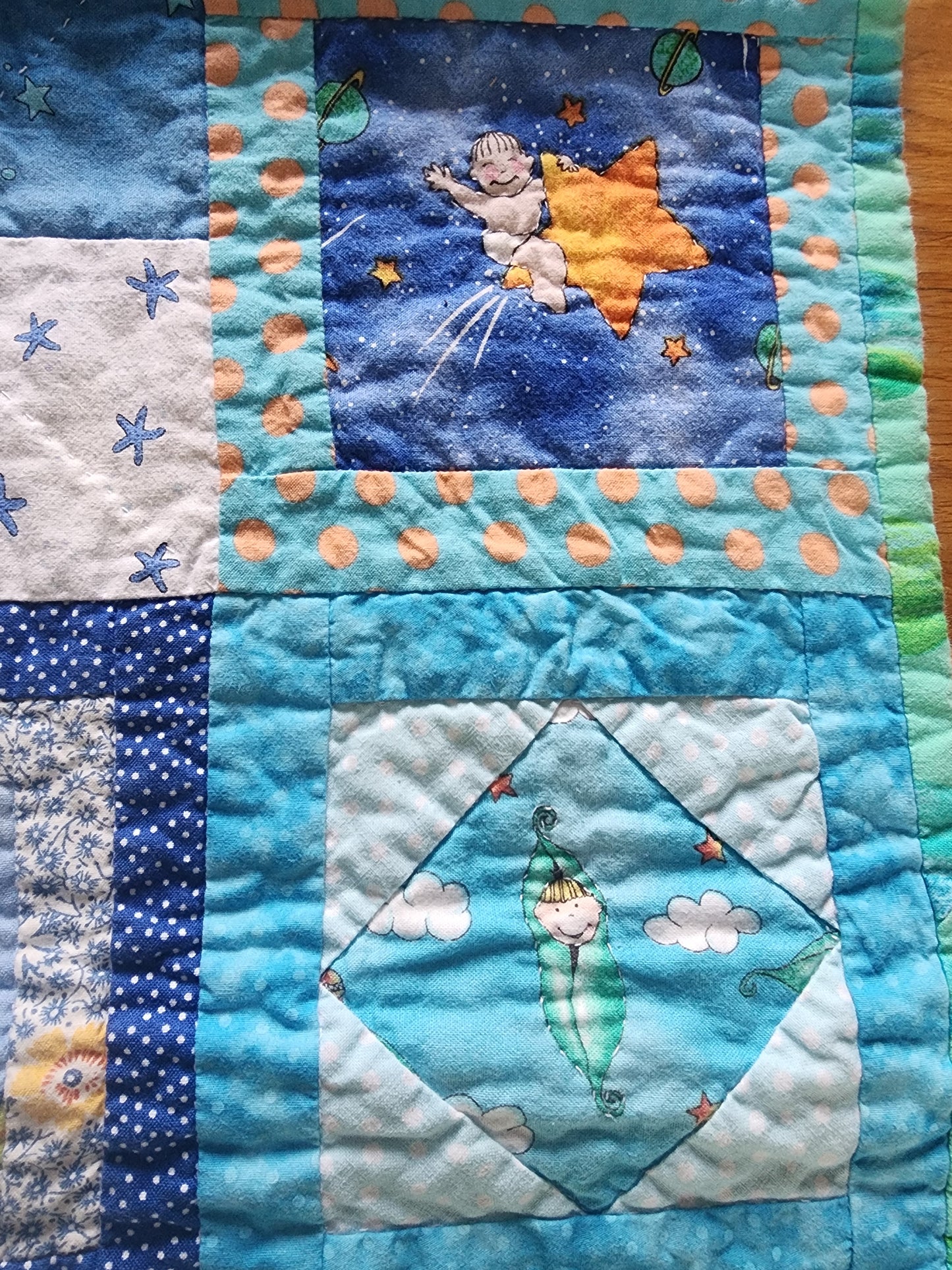 Homemade baby quilt in blues greens and Yellows baby's riding stars.