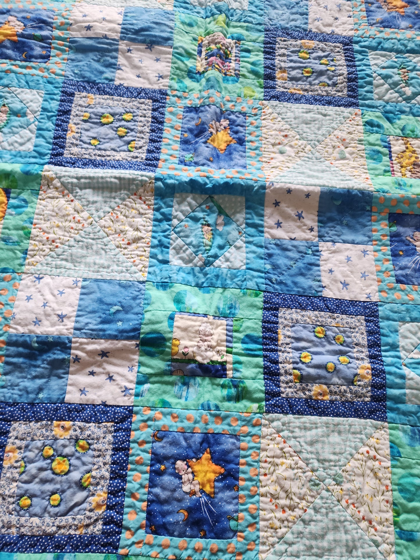 Homemade baby quilt in blues greens and Yellows baby's riding stars.