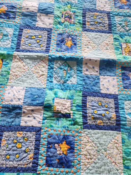 Homemade baby quilt in blues greens and Yellows baby's riding stars.