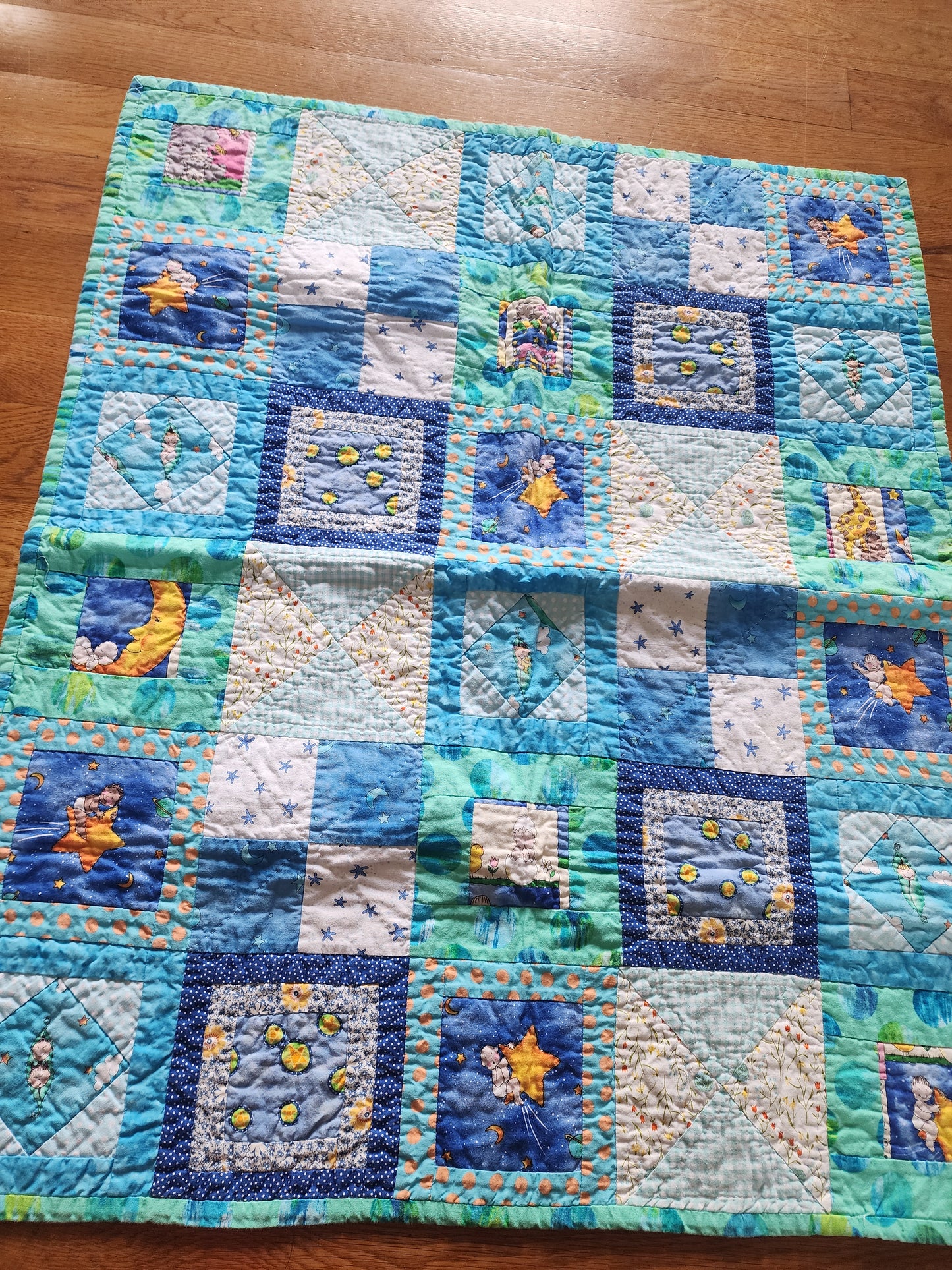Homemade baby quilt in blues greens and Yellows baby's riding stars.